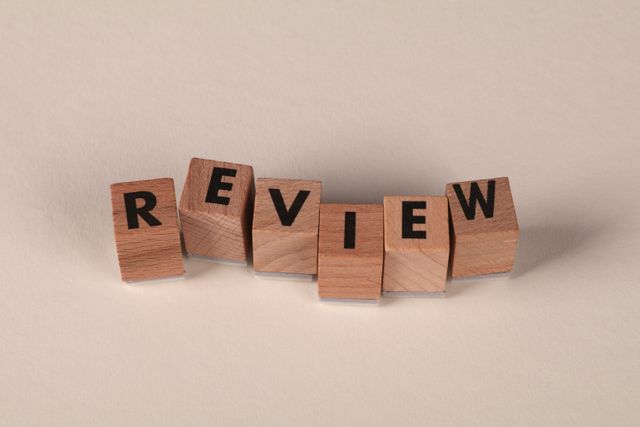 Wooden blocks with letters forming the word 'Review' on a soft pastel background.
